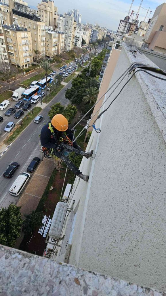 איש סנפלינג בודק ומתקן קיר חיצוני של בניין כדי לעצור חדירת רטיבות